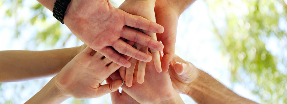 Henkilöstövoimavarat sivun headerkuva tiimin kädet yhdessä ennen tsemppaushuutoa
